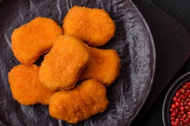 Delicious fresh crispy chicken nuggets on a dark concrete background. Unhealthy food, fast food
