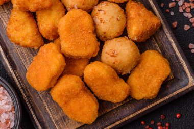 Fast food brie kızartması, peynir topları ve arka planda tavuk nuggetları.