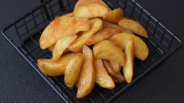 Koyu arkaplanda peynirli ve otlu fırında patates dilimleri. Ev yapımı organik sebze vejetaryen patates dilimleri.