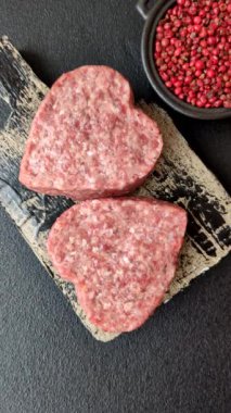 Tuzlu, baharatlı ve otlu kalp şeklinde çiğ biftek veya domuz burger köftesi.