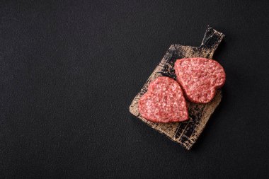 Raw beef or pork burger patty in the shape of a heart with salt, spices and herbs clipart