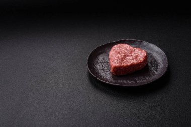 Tuzlu, baharatlı ve otlu kalp şeklinde çiğ biftek veya domuz burger köftesi.