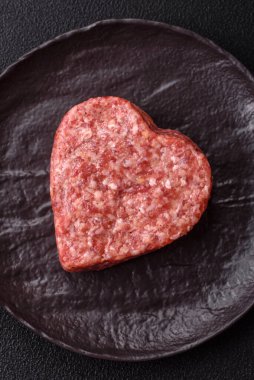 Tuzlu, baharatlı ve otlu kalp şeklinde çiğ biftek veya domuz burger köftesi.