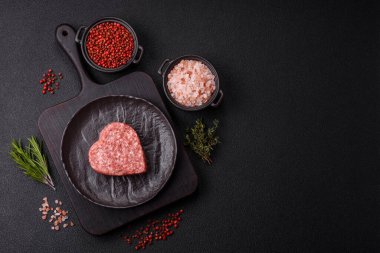 Tuzlu, baharatlı ve otlu kalp şeklinde çiğ biftek veya domuz burger köftesi.