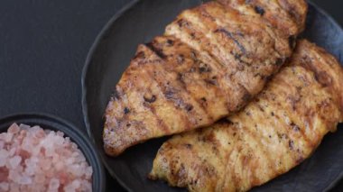 Lezzetli taze ızgara tavuk filetosu, esrarlı baharatlar ve çimento kaplı otlar. Ateşte pişirilmiş bir tabak.