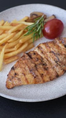 Lezzetli taze ızgara tavuk filetosu, esrarlı baharatlar ve çimento kaplı otlar. Ateşte pişirilmiş bir tabak.