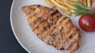 Lezzetli taze ızgara tavuk filetosu, esrarlı baharatlar ve çimento kaplı otlar. Ateşte pişirilmiş bir tabak.