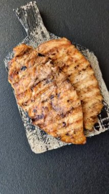 Lezzetli taze ızgara tavuk filetosu, esrarlı baharatlar ve çimento kaplı otlar. Ateşte pişirilmiş bir tabak.