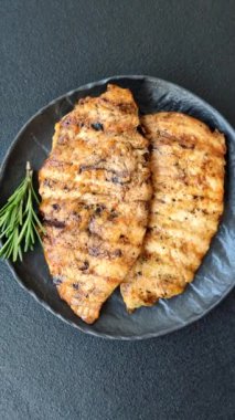 Lezzetli taze ızgara tavuk filetosu, esrarlı baharatlar ve çimento kaplı otlar. Ateşte pişirilmiş bir tabak.