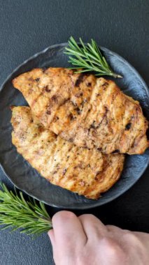 Lezzetli taze ızgara hindi filetosu, koyu beton arka planda baharatlar ve otlar. Ateşte pişirilmiş bir tabak.