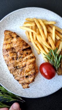 Lezzetli taze ızgara tavuk filetosu, esrarlı baharatlar ve çimento kaplı otlar. Ateşte pişirilmiş bir tabak.