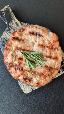 Lezzetli taze ızgara hindi filetosu, koyu beton arka planda baharatlar ve otlar. Ateşte pişirilmiş bir tabak.