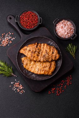 Lezzetli taze ızgara tavuk filetosu, esrarlı baharatlar ve çimento kaplı otlar. Ateşte pişirilmiş bir tabak.