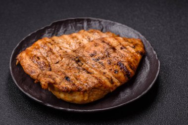 Lezzetli taze ızgara tavuk filetosu, esrarlı baharatlar ve çimento kaplı otlar. Ateşte pişirilmiş bir tabak.