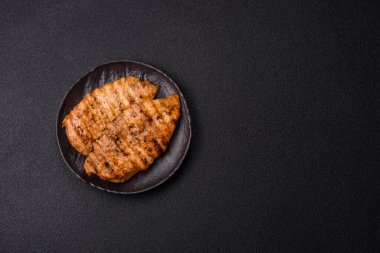 Lezzetli taze ızgara tavuk filetosu, esrarlı baharatlar ve çimento kaplı otlar. Ateşte pişirilmiş bir tabak.