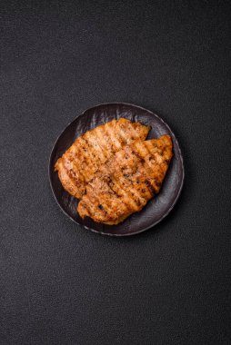 Lezzetli taze ızgara tavuk filetosu, esrarlı baharatlar ve çimento kaplı otlar. Ateşte pişirilmiş bir tabak.