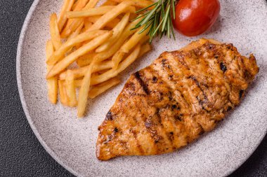 Lezzetli taze ızgara tavuk filetosu, esrarlı baharatlar ve çimento kaplı otlar. Ateşte pişirilmiş bir tabak.