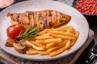 Lezzetli taze ızgara tavuk filetosu, esrarlı baharatlar ve çimento kaplı otlar. Ateşte pişirilmiş bir tabak.