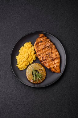 Lezzetli taze ızgara tavuk filetosu, esrarlı baharatlar ve çimento kaplı otlar. Ateşte pişirilmiş bir tabak.