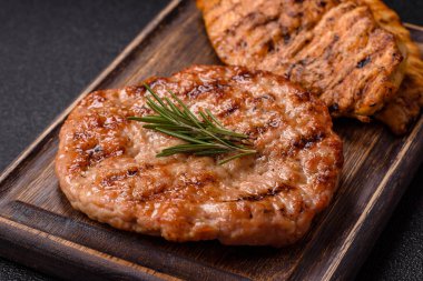 Lezzetli taze ızgara hindi filetosu, koyu beton arka planda baharatlar ve otlar. Ateşte pişirilmiş bir tabak.