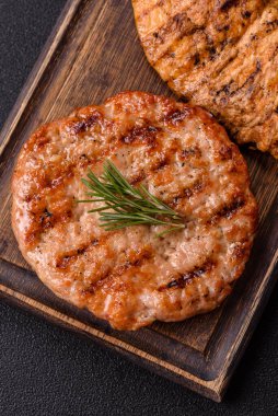 Lezzetli taze ızgara hindi filetosu, koyu beton arka planda baharatlar ve otlar. Ateşte pişirilmiş bir tabak.