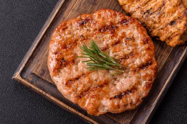 Lezzetli taze ızgara hindi filetosu, koyu beton arka planda baharatlar ve otlar. Ateşte pişirilmiş bir tabak.