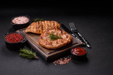 Lezzetli taze ızgara hindi filetosu, koyu beton arka planda baharatlar ve otlar. Ateşte pişirilmiş bir tabak.