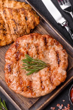 Lezzetli taze ızgara hindi filetosu, koyu beton arka planda baharatlar ve otlar. Ateşte pişirilmiş bir tabak.