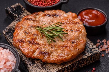 Lezzetli taze ızgara hindi filetosu, koyu beton arka planda baharatlar ve otlar. Ateşte pişirilmiş bir tabak.