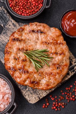 Lezzetli taze ızgara hindi filetosu, koyu beton arka planda baharatlar ve otlar. Ateşte pişirilmiş bir tabak.