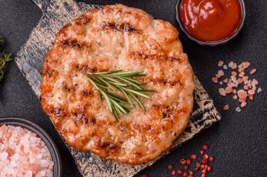 Lezzetli taze ızgara hindi filetosu, koyu beton arka planda baharatlar ve otlar. Ateşte pişirilmiş bir tabak.