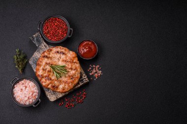 Lezzetli taze ızgara hindi filetosu, koyu beton arka planda baharatlar ve otlar. Ateşte pişirilmiş bir tabak.