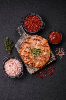 Lezzetli taze ızgara hindi filetosu, koyu beton arka planda baharatlar ve otlar. Ateşte pişirilmiş bir tabak.