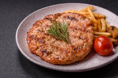 Lezzetli taze ızgara hindi filetosu, koyu beton arka planda baharatlar ve otlar. Ateşte pişirilmiş bir tabak.