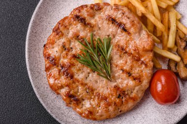 Lezzetli taze ızgara hindi filetosu, koyu beton arka planda baharatlar ve otlar. Ateşte pişirilmiş bir tabak.