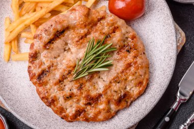 Lezzetli taze ızgara hindi filetosu, koyu beton arka planda baharatlar ve otlar. Ateşte pişirilmiş bir tabak.