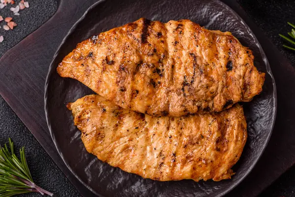 Lezzetli taze ızgara tavuk filetosu, esrarlı baharatlar ve çimento kaplı otlar. Ateşte pişirilmiş bir tabak.