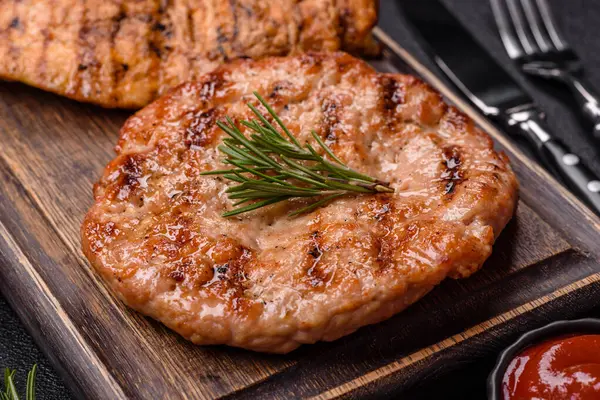 Lezzetli taze ızgara hindi filetosu, koyu beton arka planda baharatlar ve otlar. Ateşte pişirilmiş bir tabak.