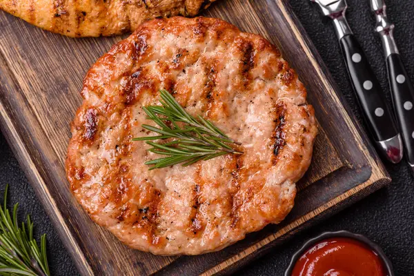 Lezzetli taze ızgara hindi filetosu, koyu beton arka planda baharatlar ve otlar. Ateşte pişirilmiş bir tabak.