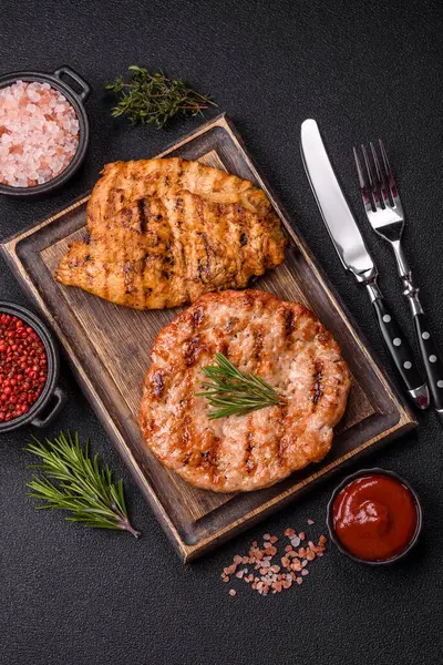 Lezzetli taze ızgara hindi filetosu, koyu beton arka planda baharatlar ve otlar. Ateşte pişirilmiş bir tabak.