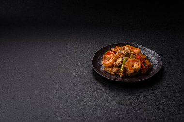 Karidesli pilav ve deniz ürünleri, sebze, baharat ve soya sosu koyu beton arka planda.