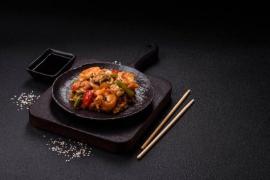 Karidesli pilav ve deniz ürünleri, sebze, baharat ve soya sosu koyu beton arka planda.