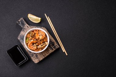 Karidesli pilav ve deniz ürünleri, sebze, baharat ve soya sosu koyu beton arka planda.