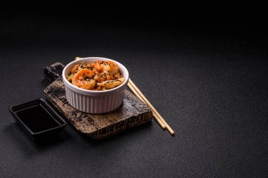 Karidesli pilav ve deniz ürünleri, sebze, baharat ve soya sosu koyu beton arka planda.