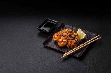 Karidesli pilav ve deniz ürünleri, sebze, baharat ve soya sosu koyu beton arka planda.