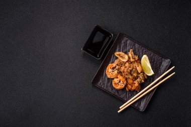 Karidesli pilav ve deniz ürünleri, sebze, baharat ve soya sosu koyu beton arka planda.