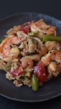 Karidesli pilav ve deniz ürünleri, sebze, baharat ve soya sosu koyu beton arka planda.