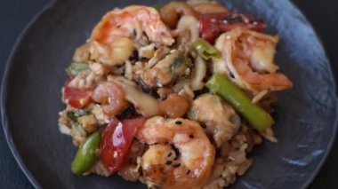 Karidesli pilav ve deniz ürünleri, sebze, baharat ve soya sosu koyu beton arka planda.