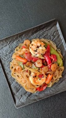 Karides, deniz mahsulü, sebze, baharat ve soya soslu, koyu beton kaplama erişte.