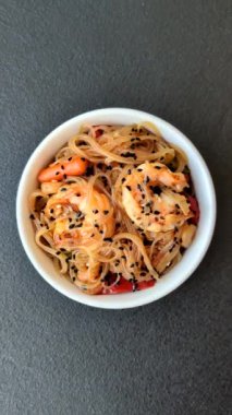 Karides, deniz mahsulü, sebze, baharat ve soya soslu, koyu beton kaplama erişte.